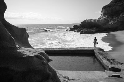 grayscale-photo-of-person-walking-on-wooden-dock