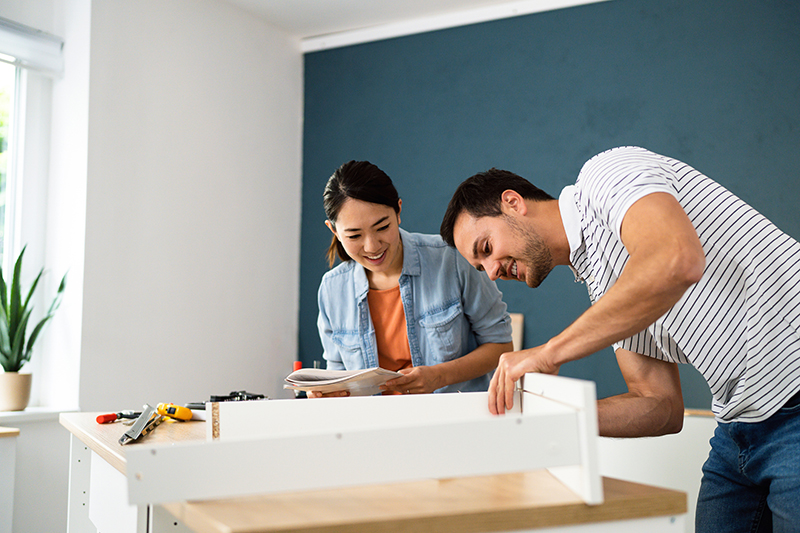 Couple assembling furniture together at their new apartment