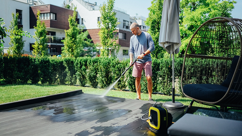 Man cleaning his veranda with high pressure washer
