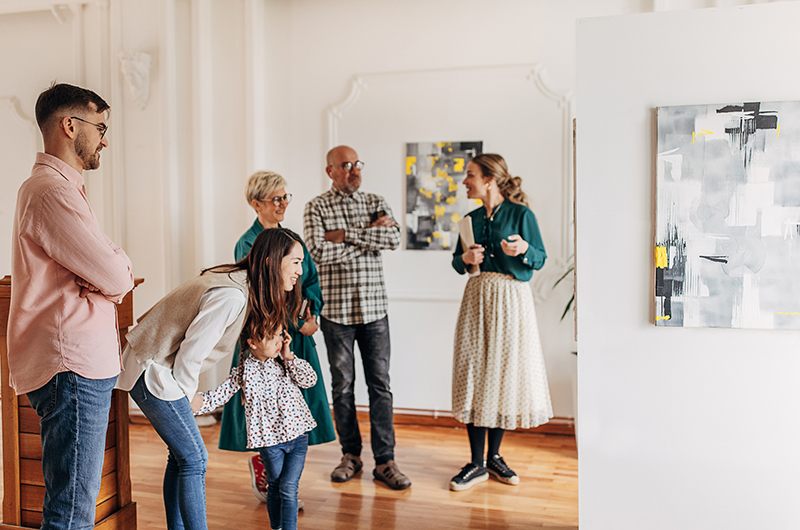 Gallery opening day, female gallery owner showing and explaining art to an interested group of visitors.