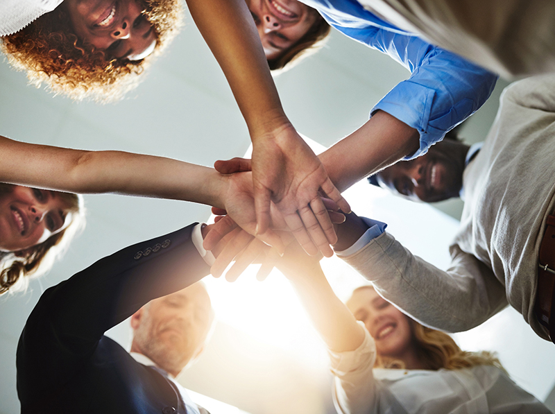 Low angle shot of a group of colleagues joining their hands in solidarity