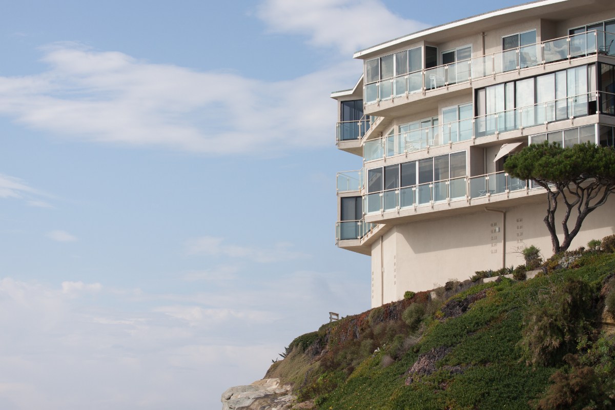 Modern multi-story residential building with glass balconies on a Laguna Beach cliff
